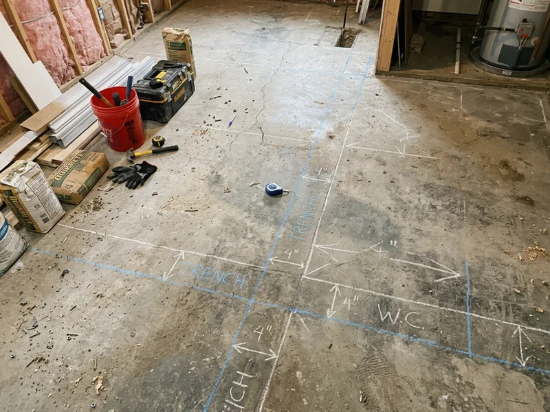 Basement slab marked with chalk lines for a new plumbing trench