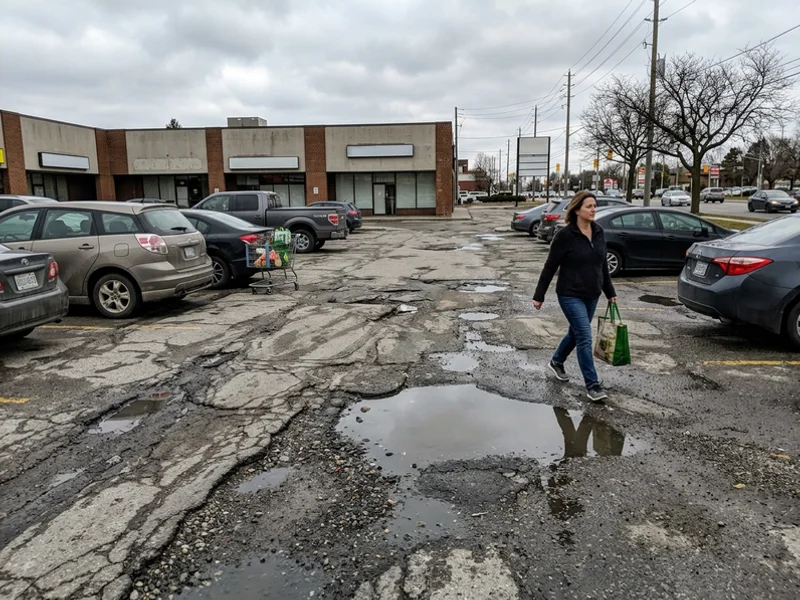 Deteriorated asphalt lot with potholes and ponding before replacement