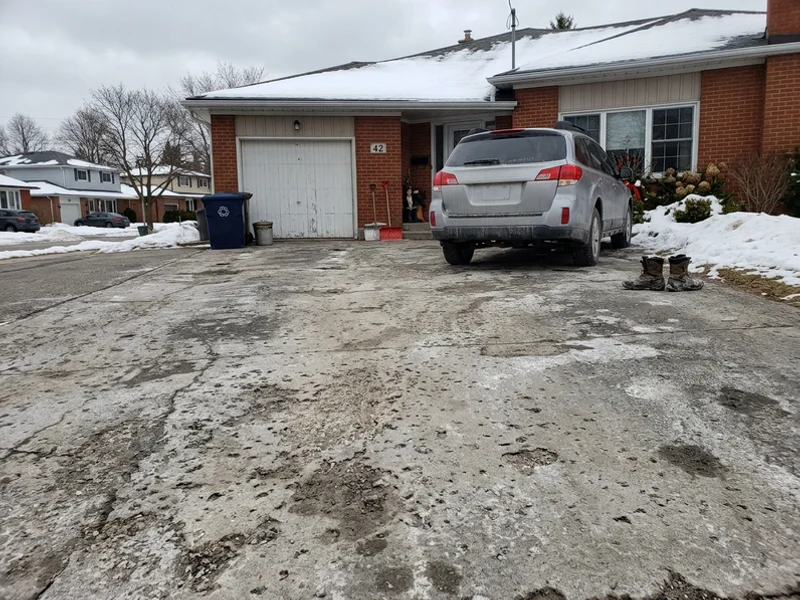 Unsealed driveway showing early scaling and salt damage